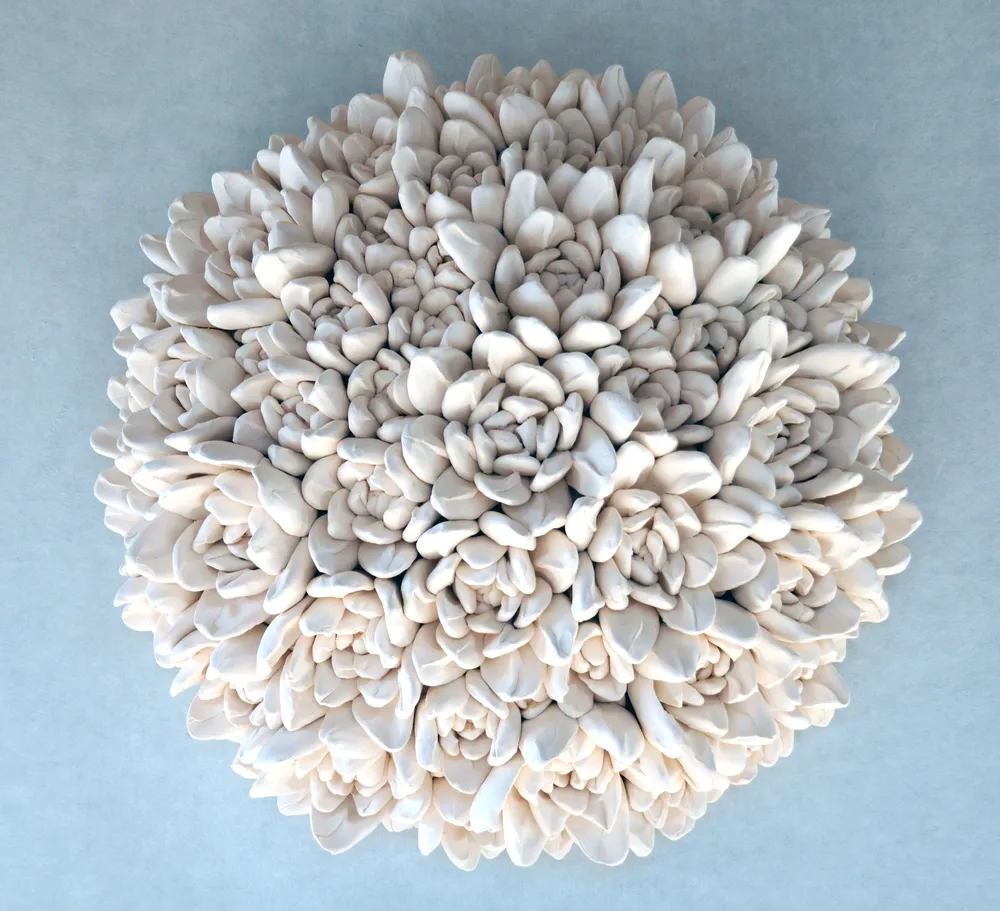A round wall cluster of pointed white porcelain rosettes, larger at the rim and tightening towards the centre, on a blue-grey ground.