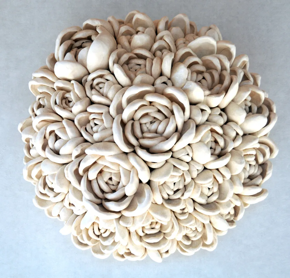 A round wall cluster of large cream cabbage-rose-like echeveria forms in matte unglazed porcelain.