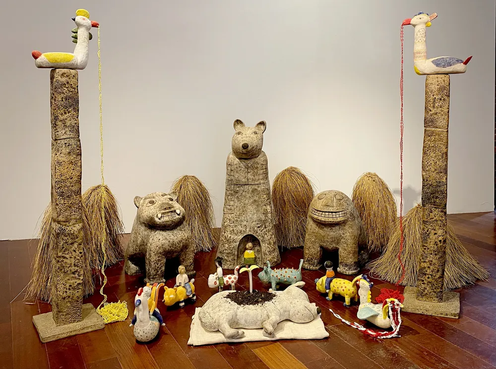 Memorial for Dory installed at Boston Sculptors Gallery: the bear Totem at the centre with two Jinmyosoo beasts and seagrass Teojugali bundles beside it, small kokdu figures in a row, the dog Dory lying on a cloth in front, and two Bonghwang bird-poles holding long strings in their beaks.