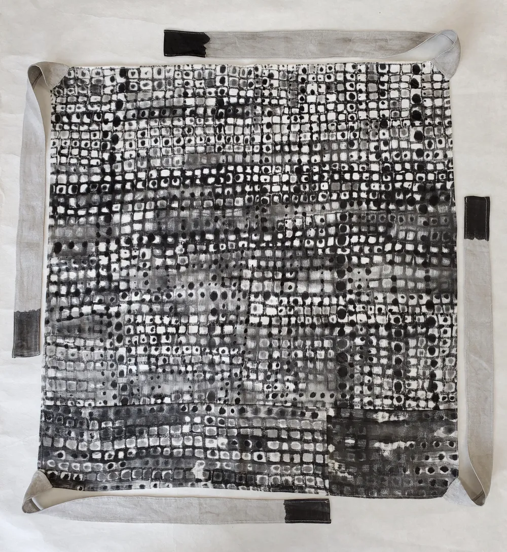 Where or When / Tribute to Kim Whanki, a square cloth bojagi covered edge to edge in a grid of small ink squares with dots, with dark tabs at the top, right and bottom edges.