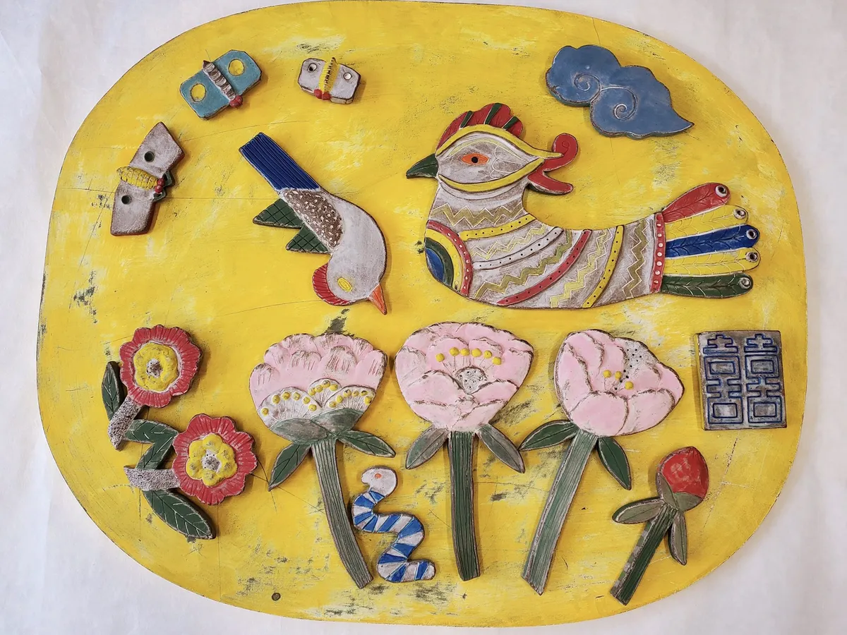 Talisman panel: a bird, peonies and small ceramic charms on a yellow ground