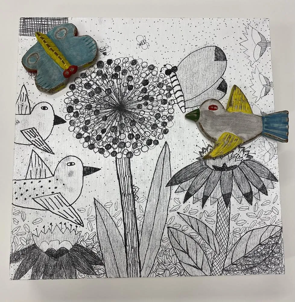 A square talisman panel drawn in fine black line with dandelion clocks, coneflowers and birds, with a blue-and-yellow ceramic butterfly and a yellow-winged ceramic bird attached to the surface.