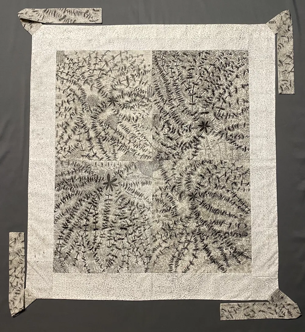 A square bojagi shot flat on grey: a dense all-over sumi-ink drawing of seed pods, fern sprays and star-flowers inside a wide speckled border, with straps at the four corners.