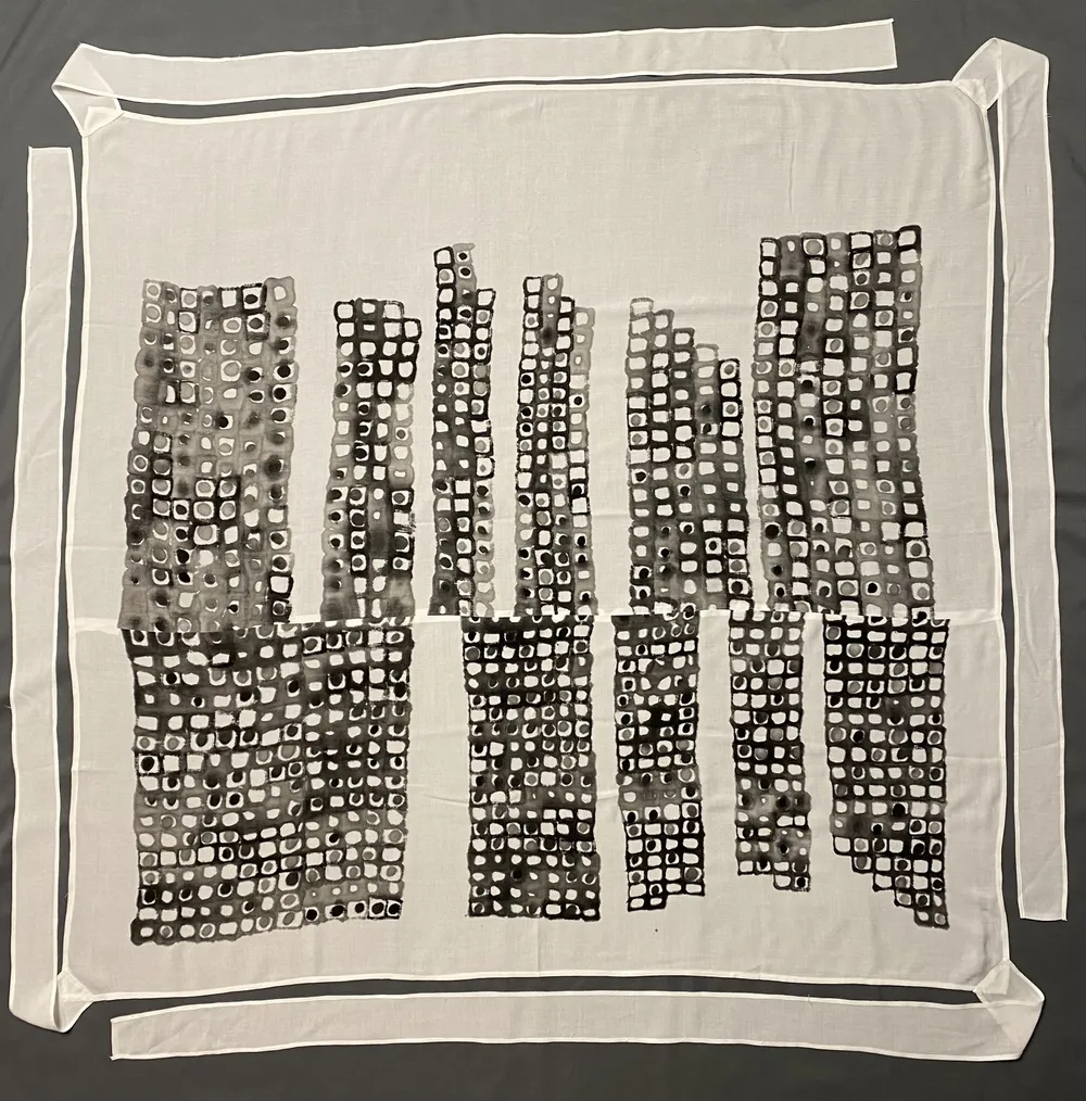 A bojagi of two tiers of columns, each brushed in sumi ink with small squares and dots, on white linen with a plain border and its straps laid out flat on grey.