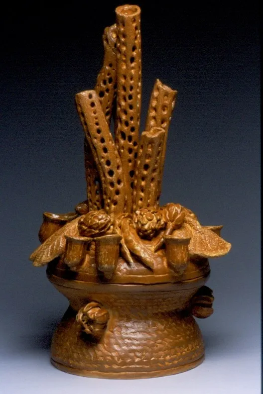 An amber-glazed censer with three perforated tubular stalks rising from a bowl of pods and cups, on a hammered footed base.