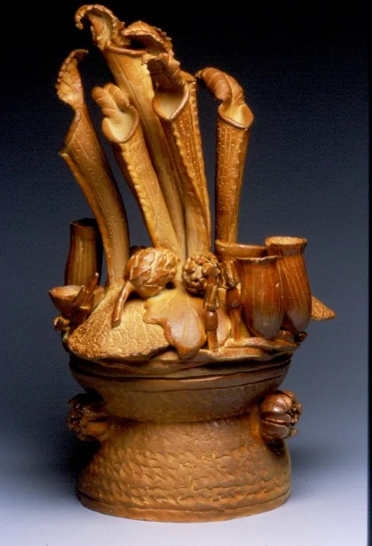An amber salt-glazed lidded censer whose lid erupts in tall pitcher-plant and leaf forms, with small cups and pods around the rim.