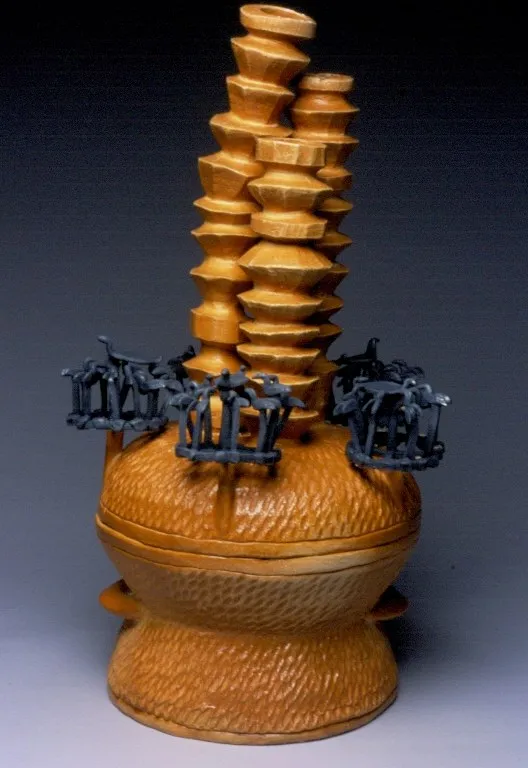 Incense Burner 1, an amber-glazed lidded censer with a tall notched pagoda tower rising from its lid and three dark blue-black clusters of tiny railings and figures around it, on a footed base.