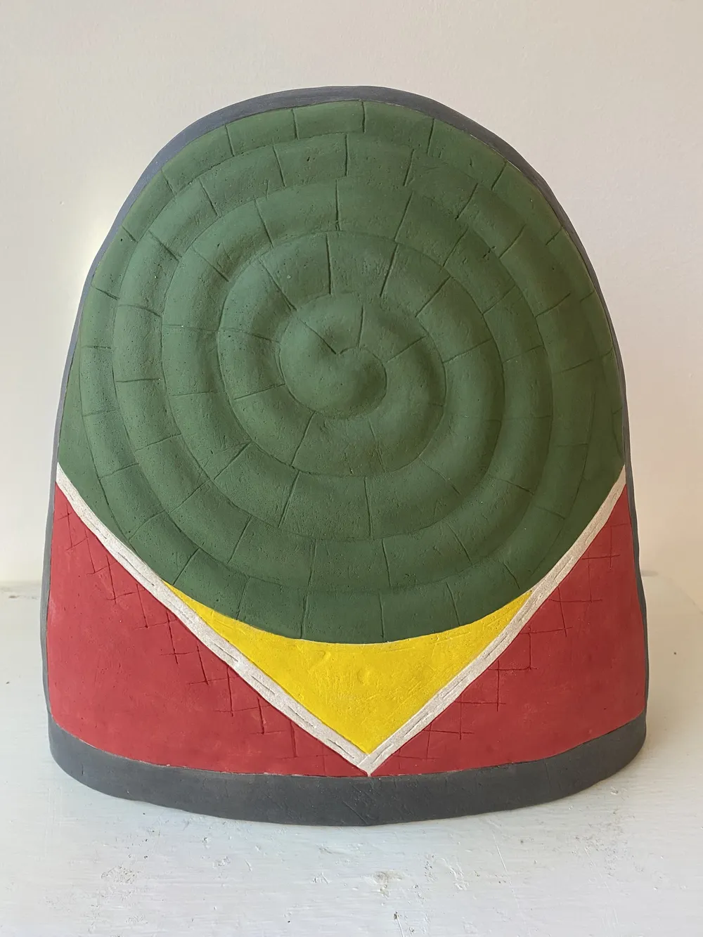 Thimble 5, a large clay thimble dome with a green concentric spiral cap over a red body, a yellow chevron below it and a dark grey rim.