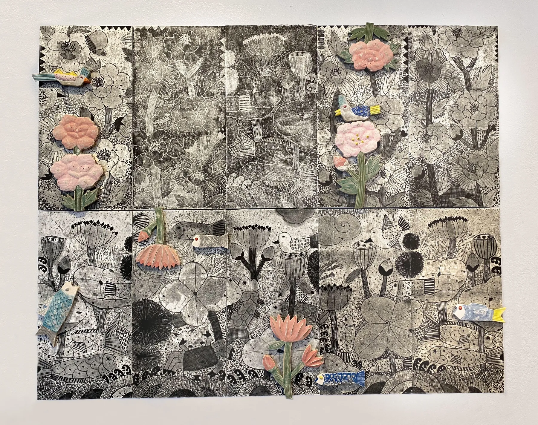 This Fertile Earth, its two large monoprinted hanji panels shown one above the other: a dense black-and-white ground of flowers, birds and underwater forms with pink ceramic peonies and small ceramic birds set on top.